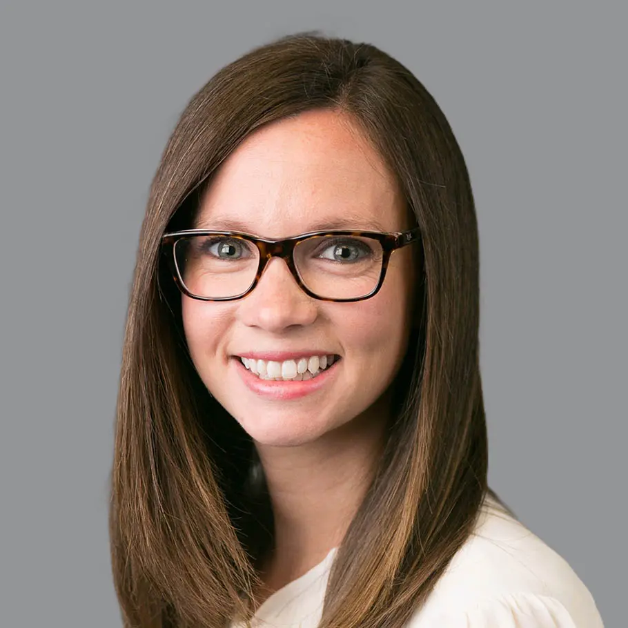 A woman with glasses is smiling for the camera.