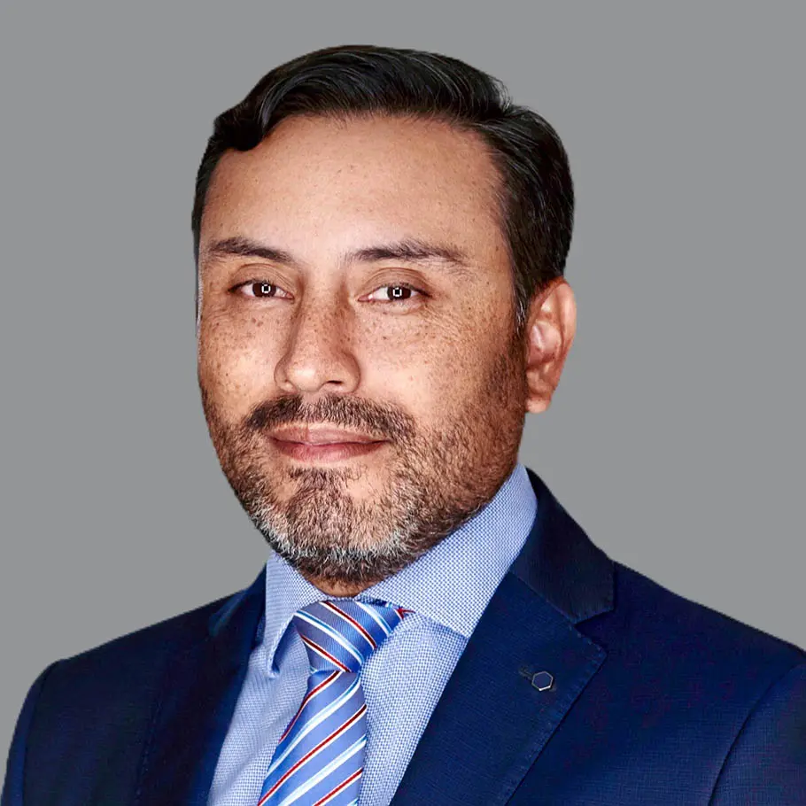 A man in a suit and tie standing up against a gray background.