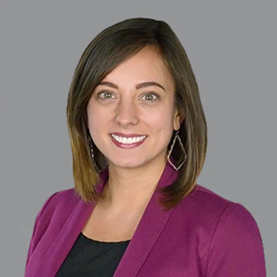 A woman in purple jacket smiling for the camera.