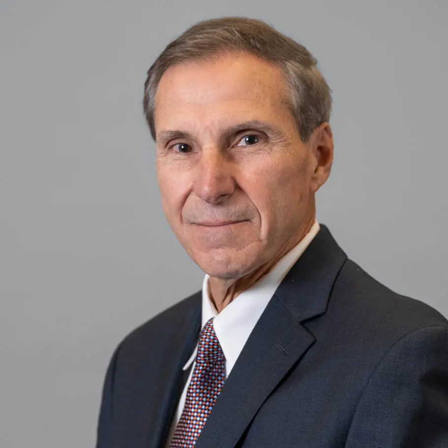 A man in a suit and tie standing up against a wall.