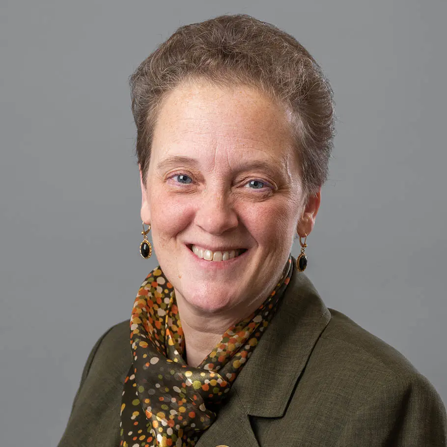 A woman with short hair and a brown jacket.