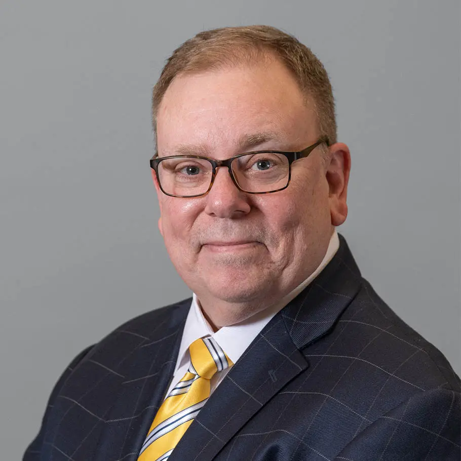 A man in a suit and tie standing next to a wall.