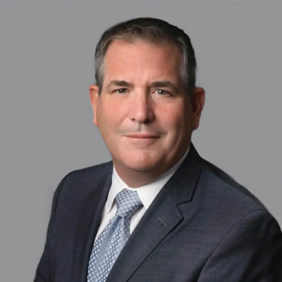 A man in suit and tie standing next to a wall.