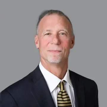 A man in suit and tie standing next to a wall.