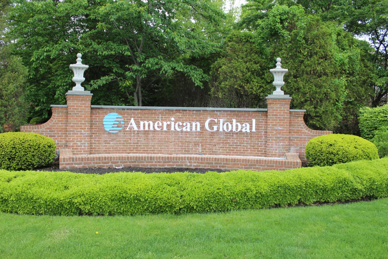 A sign that says american global in front of some trees.