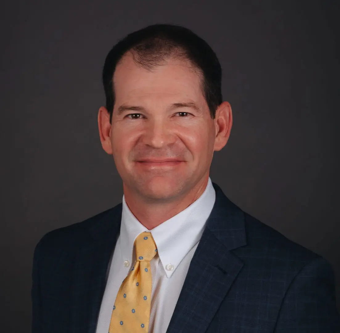 A man in a suit and tie smiling for the camera.