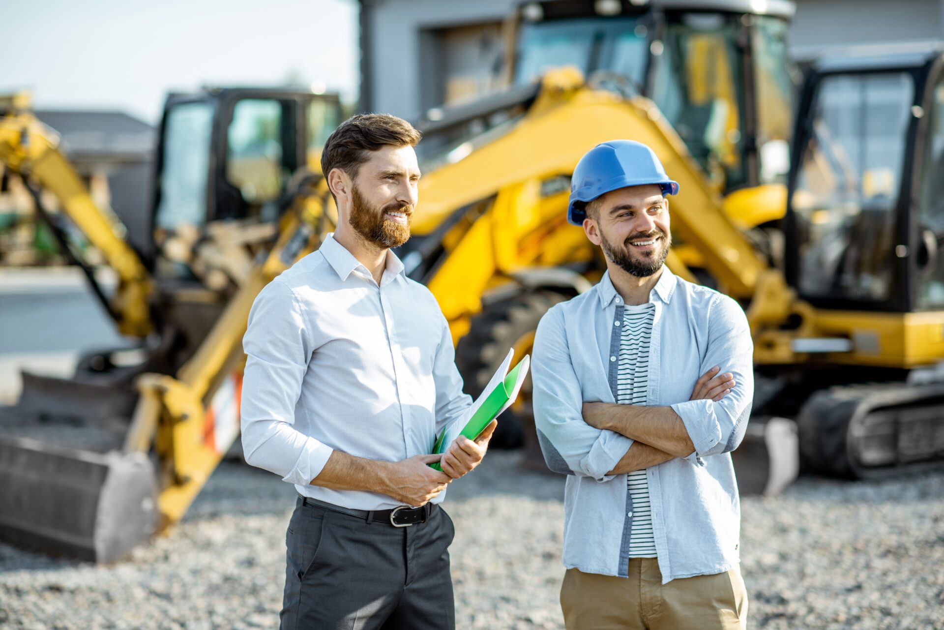 Two men standing next to each other near a construction site.