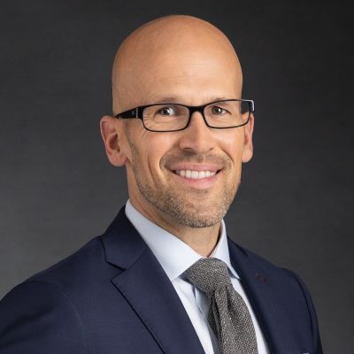 Smiling man in suit and glasses.