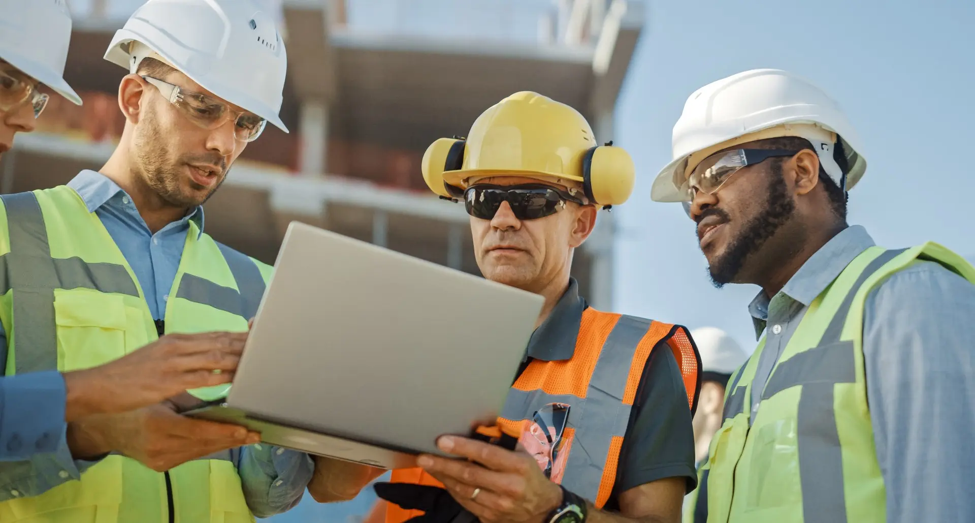 Three construction workers looking at laptop.