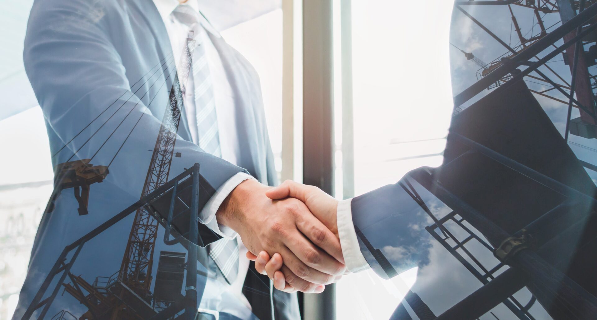 Businessmen shaking hands with construction overlay.