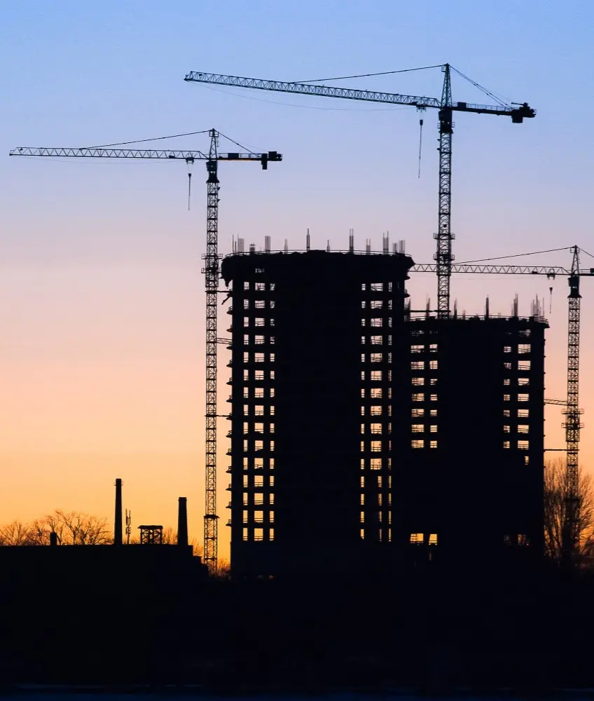 Silhouetted building under construction at sunset.