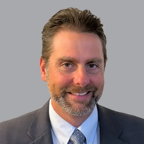 A man in a suit with a beard and a smile.