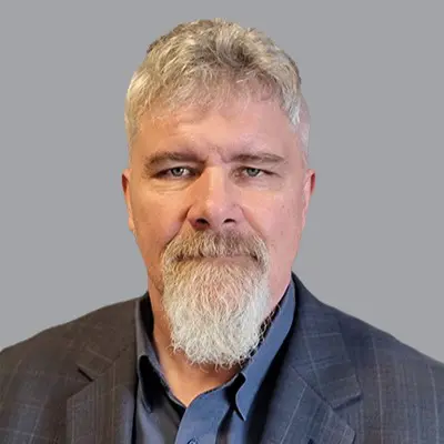 A man with gray hair and beard in a suit.