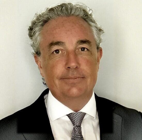 Man in suit with grey hair smiling.